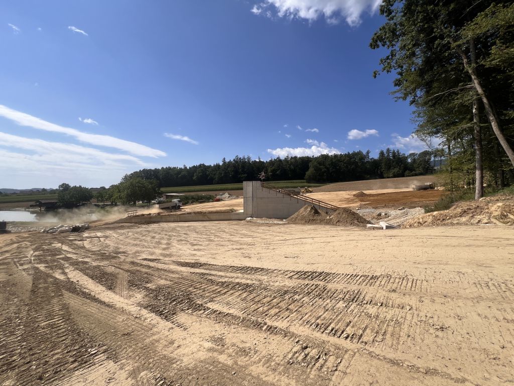 Baustelle mit Betonwand, Baggern und Lastwagen in der Steiermark
